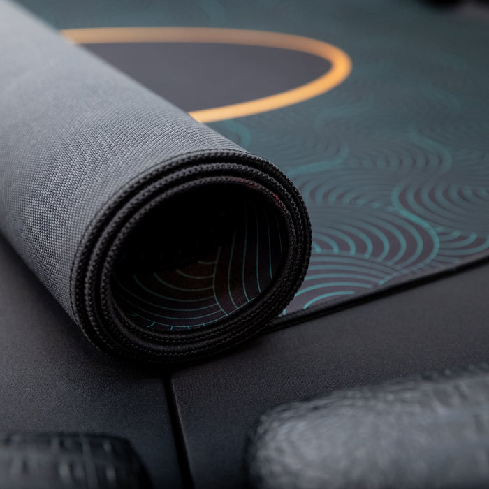 Roll of gray fabric on a textured surface with a patterned mat in the background