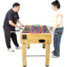 Two people playing a foosball table on a white background