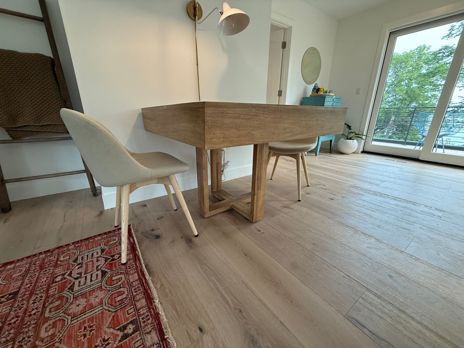 Dining area with wooden table and chairs in a well-lit room with large windows.