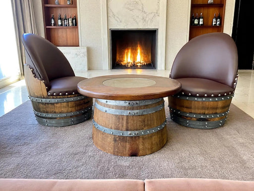 Two barrel chairs with a barrel table in front of a fireplace.