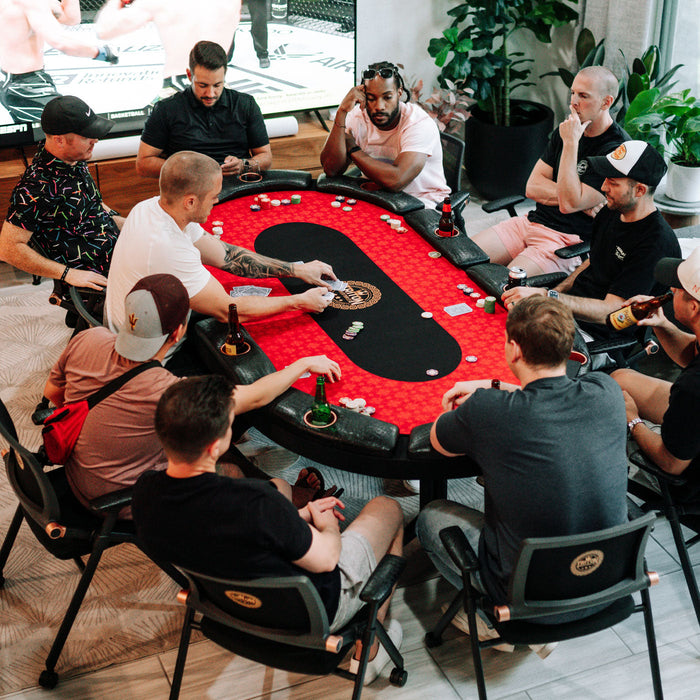 Group of people playing poker at a table with chips and cards.