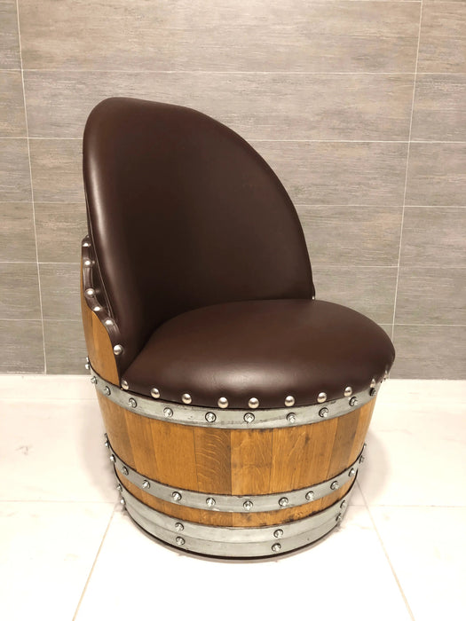 Chair made from a wooden barrel with brown leather seat against a tiled wall.