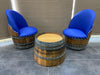 Two barrel chairs with blue cushions and a matching barrel table on a tiled floor.