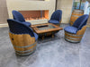 Wooden barrel chairs with blue cushions around a fire pit table.
