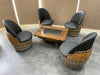 Wooden barrel chairs with black seats arranged around a wooden table on a tiled floor.