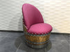 Chair made from a wine barrel with pink cushion and metal studs against a light wall.