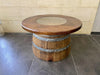 Wooden barrel table with a round top on a tiled floor.