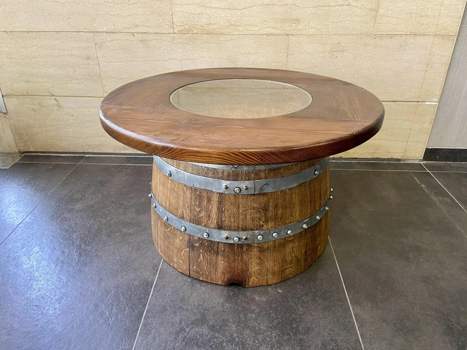 Wooden barrel table with a round top on a tiled floor.