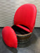 Red upholstered chair with wooden base on a tiled floor.
