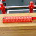 Red foosball table with numbered red rods on a wooden surface
