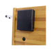 Black rectangular device attached to a wooden surface with a white pipe-like object on the left.