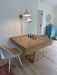 Wooden dining table with chess pieces in a room with a lamp and chairs.