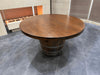 Round wooden dining table on a gray tiled floor with a neutral wall background