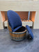 Chair made from a wooden barrel with blue cushioned seat and backrest on a tiled floor.