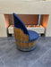 Chair made from a wine barrel with a blue cushion in front of a fireplace.