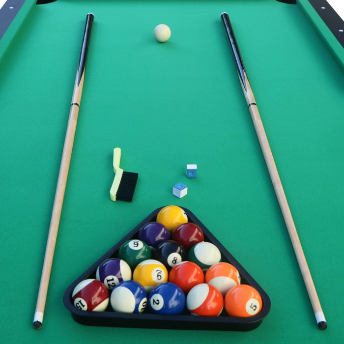 Pool table with billiard balls in a triangle rack and two cues on a green felt surface.