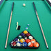 Pool table with billiard balls in a triangle rack and two cues on a green felt surface.