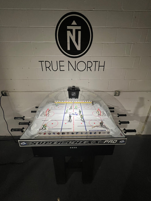 Hockey table with 'True North' branding on a white brick wall.