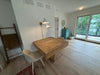 Small dining area with a wooden table and chairs in a room with large windows.