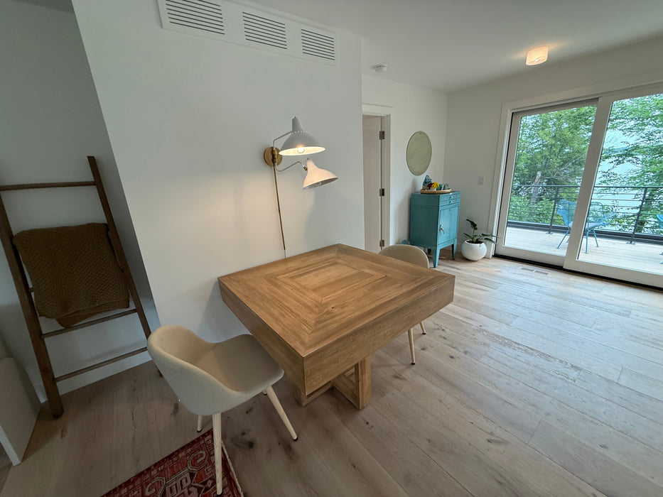 Small dining area with a wooden table and chairs in a room with large windows.