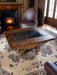 Wooden coffee table with metal legs in a room with a fireplace and curtains.