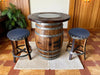 Wooden barrel table with two bar stools on a wooden floor.
