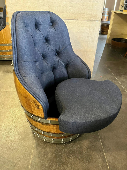 Chair made from a wine barrel with blue cushioned seat and backrest on a tiled floor.