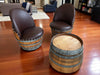 Two barrel chairs with brown leather seats on a wooden floor.