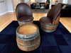 Two barrel-shaped chairs with wooden seats and metal accents on a dark blue rug in a living room.
