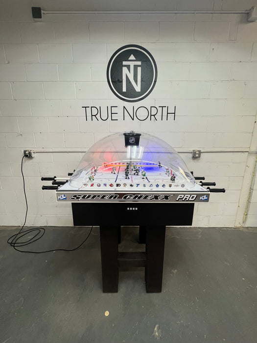 Super Game Pro air hockey table with 'True North' branding on a white brick wall.