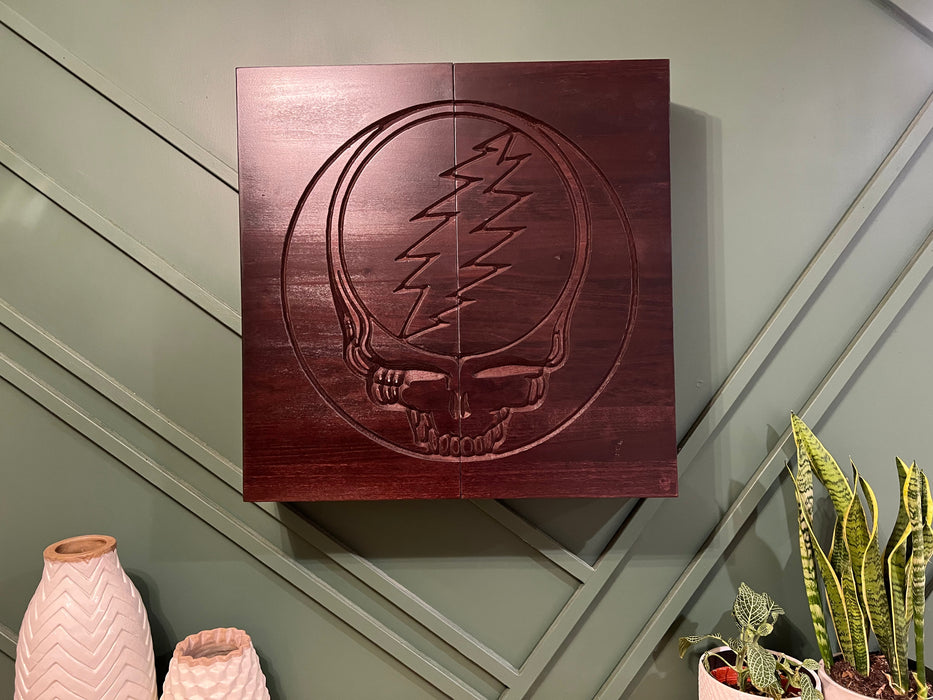 Wooden wall art with a skull and lightning bolt design on a gray wall.