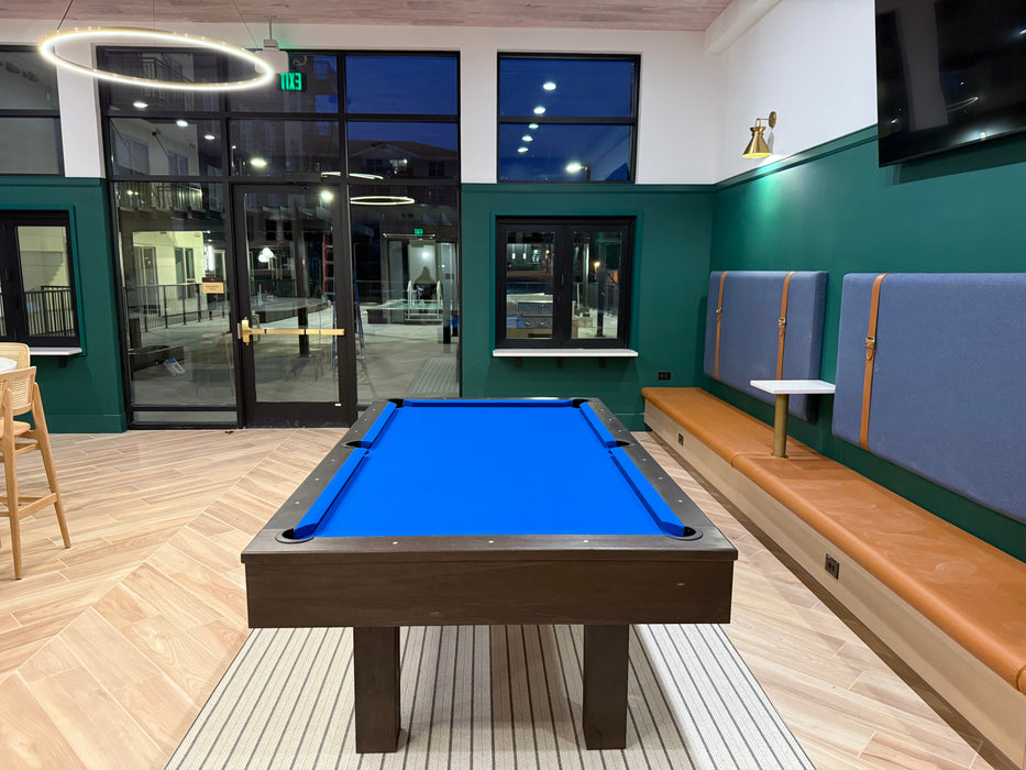 Pool table in a modern indoor setting with green walls and wooden flooring.