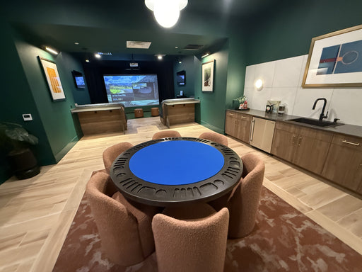 Game room with a blue poker table and chairs, TV, and kitchen area.