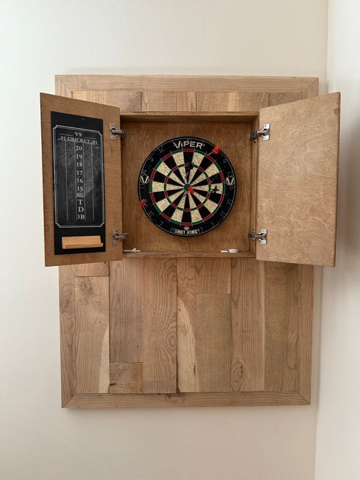 Wooden dartboard cabinet with a dartboard inside, mounted on a white wall.