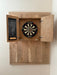 Wooden dartboard cabinet with a dartboard inside, mounted on a white wall.