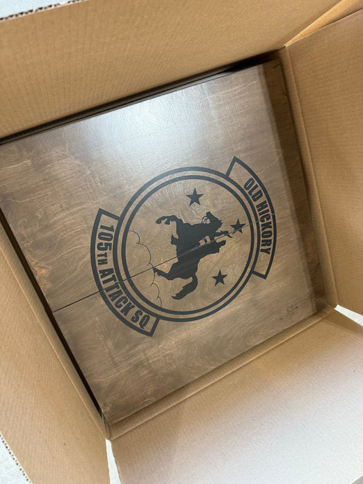 Wooden box with a engraved logo and text, likely a product packaging.
