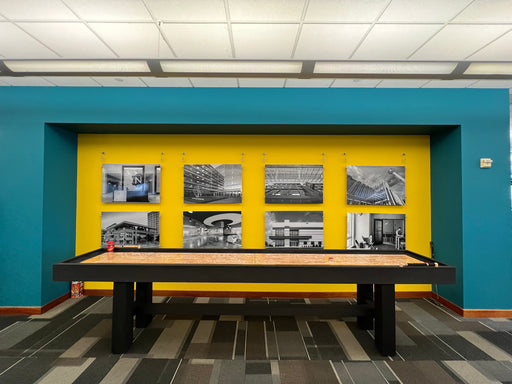 Billiard table against a blue wall with yellow accent panel featuring black and white photos