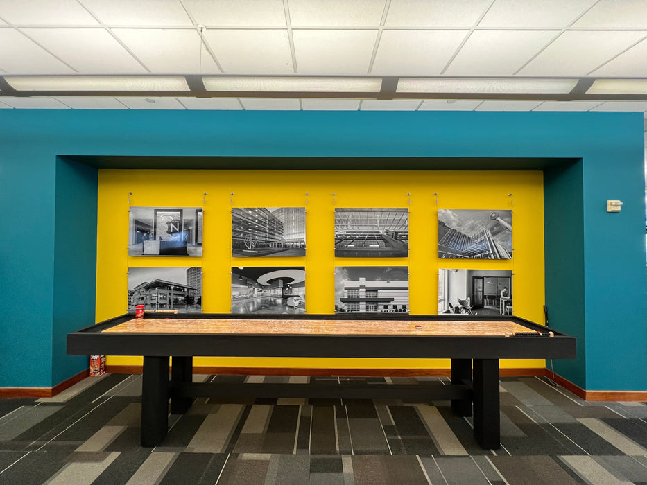 Billiard table against a blue wall with yellow accent panel featuring black and white photos