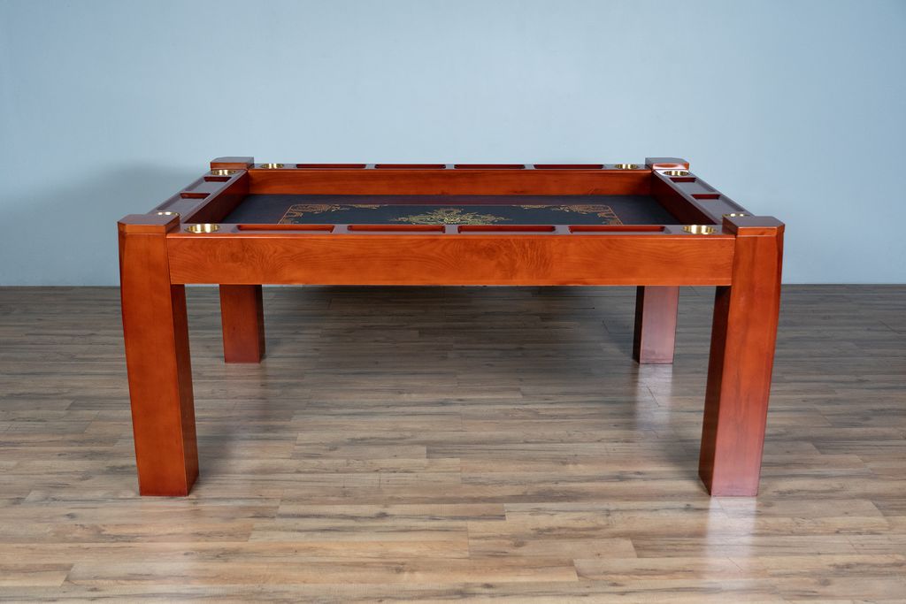 Wooden pool table with leather felt surface on a wooden floor against a gray wall.