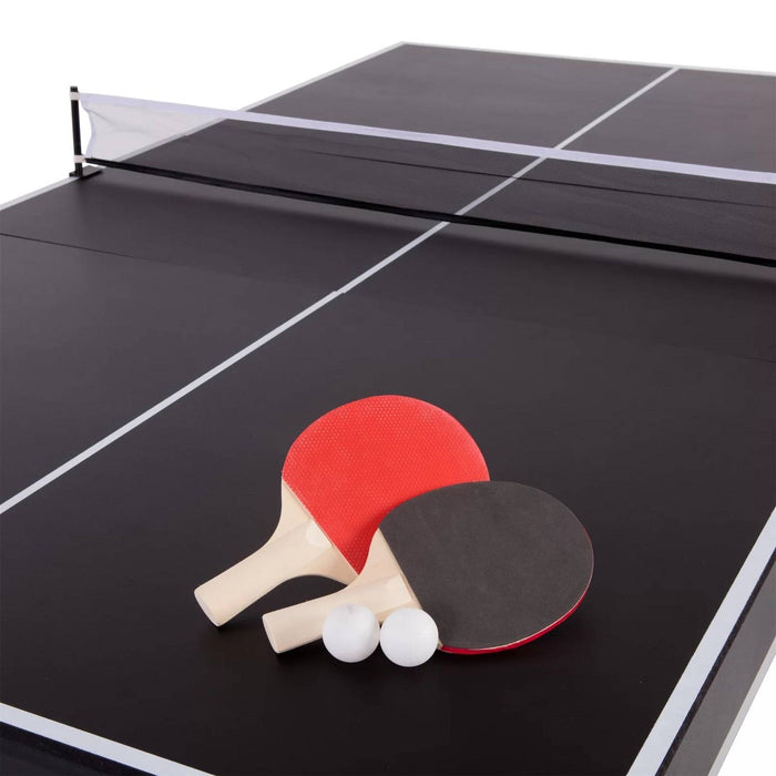 Two ping pong paddles in red and black and two white balls on a black table tennis table.