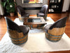 Wooden barrel chairs with a table in a room with a fireplace and shelves.