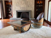 Wooden barrel chairs and table in a room with stone fireplace and shelves.