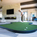 Man playing indoor putting green in a modern living room.
