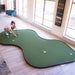 Person playing indoor putting green in a room with large windows.