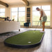 Man playing mini golf in a living room with large windows.