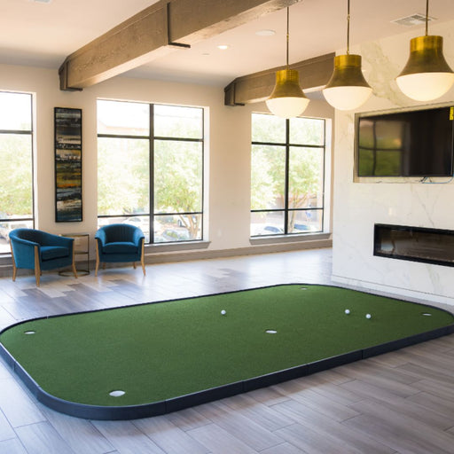 Indoor putting green area with chairs and a television in a modern room.