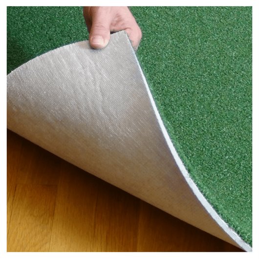 Green artificial grass being peeled back to reveal a white underlayer.