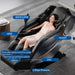 Woman using a massage chair with labeled parts on a gray floor.