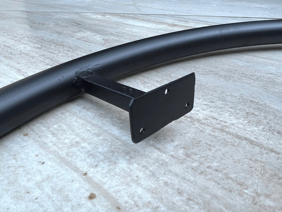 Black metal bracket attached to a black pipe on a concrete surface