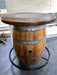 Wooden barrel table with metal bands on a concrete floor.